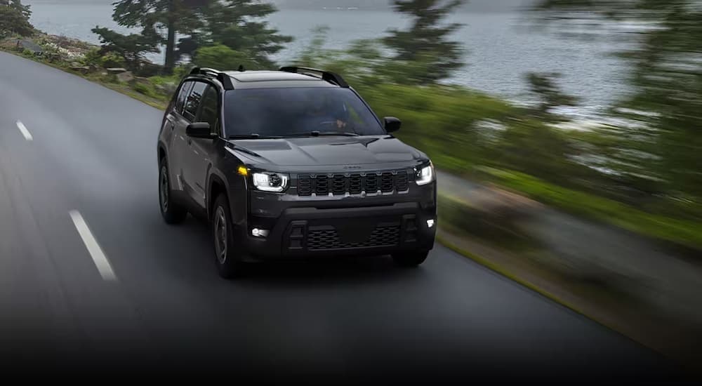 A black 2026 Jeep Cherokee for sale driving on a highway.