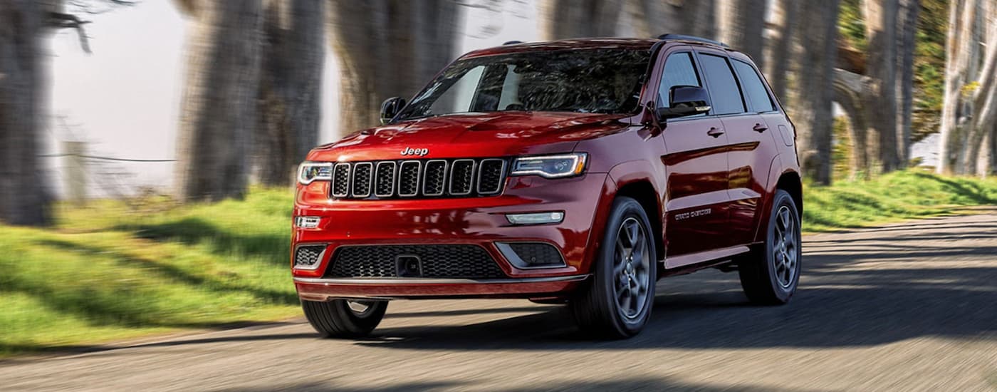 Red 2020 Jeep Grand Cherokee driving down an open road.