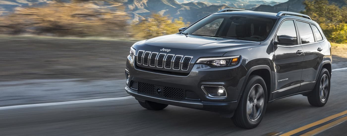 Black 2021 Jeep Cherokee driving down an open road.