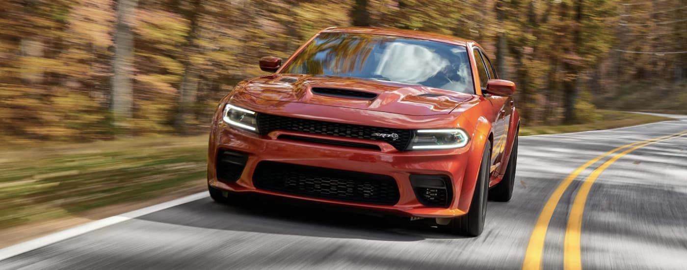 Orange 2022 Dodge Charger SRT Hellcat driving on a paved road.