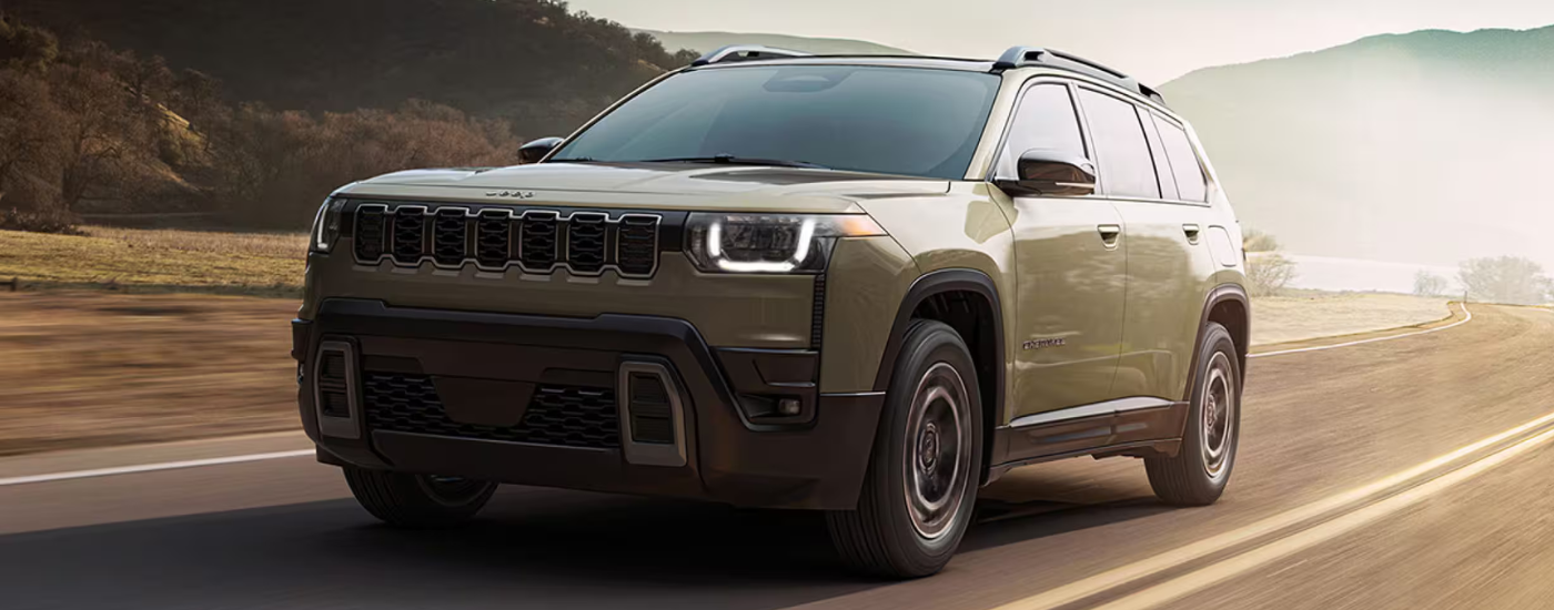 Green 2026 Jeep Cherokee driving on a desert road