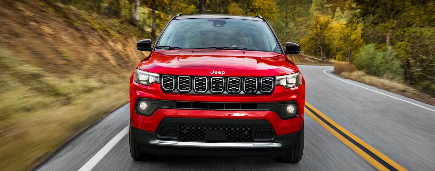 Front of a red 2026 Jeep Compass driving on a winding road