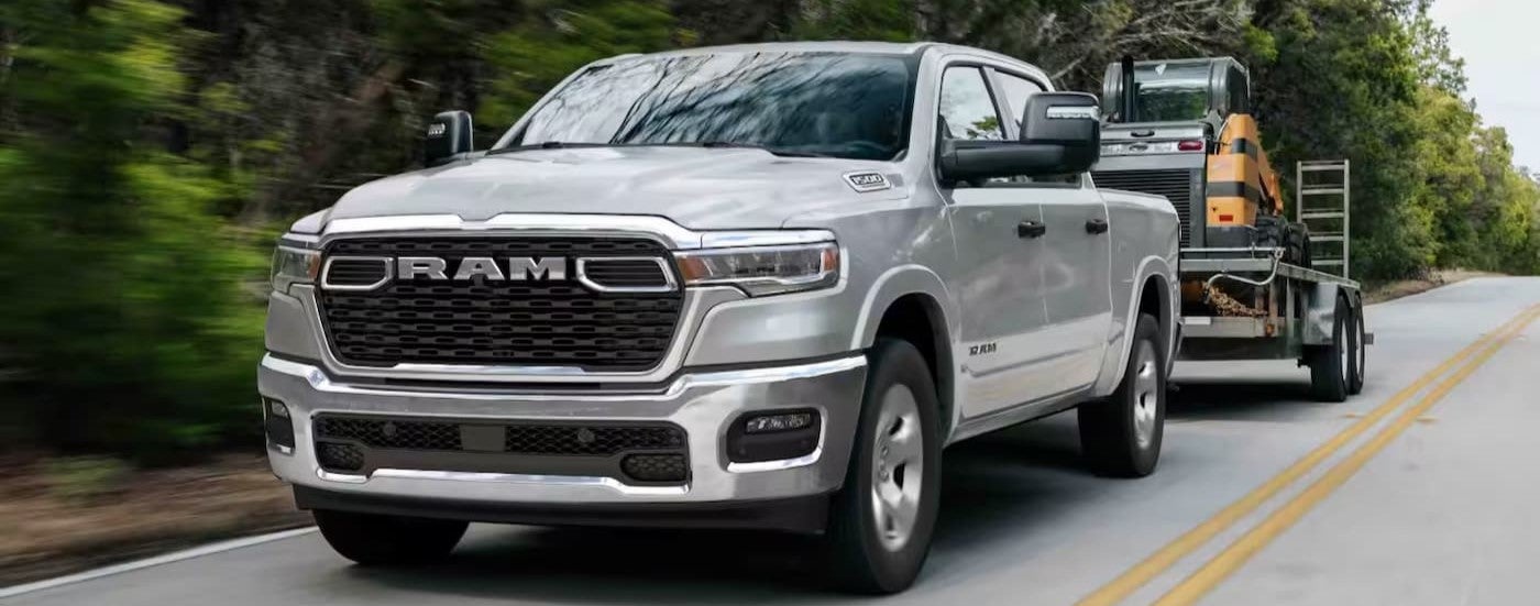 The silver 2026 Ram 1500 Big Horn towing a trailer.