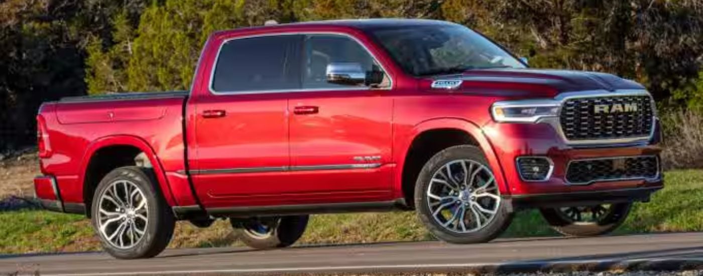 Red 2026 Ram 1500 driving on a country road.