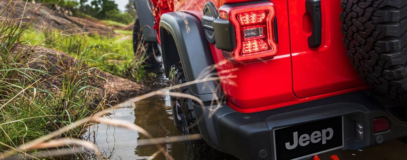 Red 2026 Jeep Wrangler rear view up close driving through a puddle.