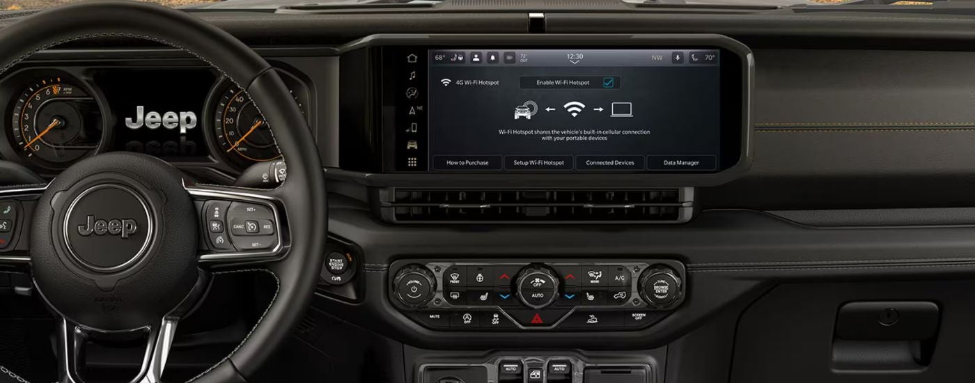 2026 Jeep Wrangler front interior showing steering wheel and infotainment display.