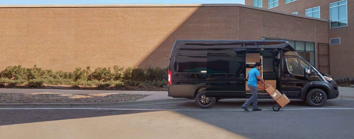 A person loading boxes into a grey 2024 Ram ProMaster.