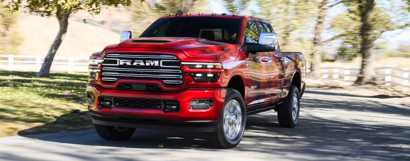 Red 2026 Ram 1500 driving down a road from a Ram dealer near Dimondale.